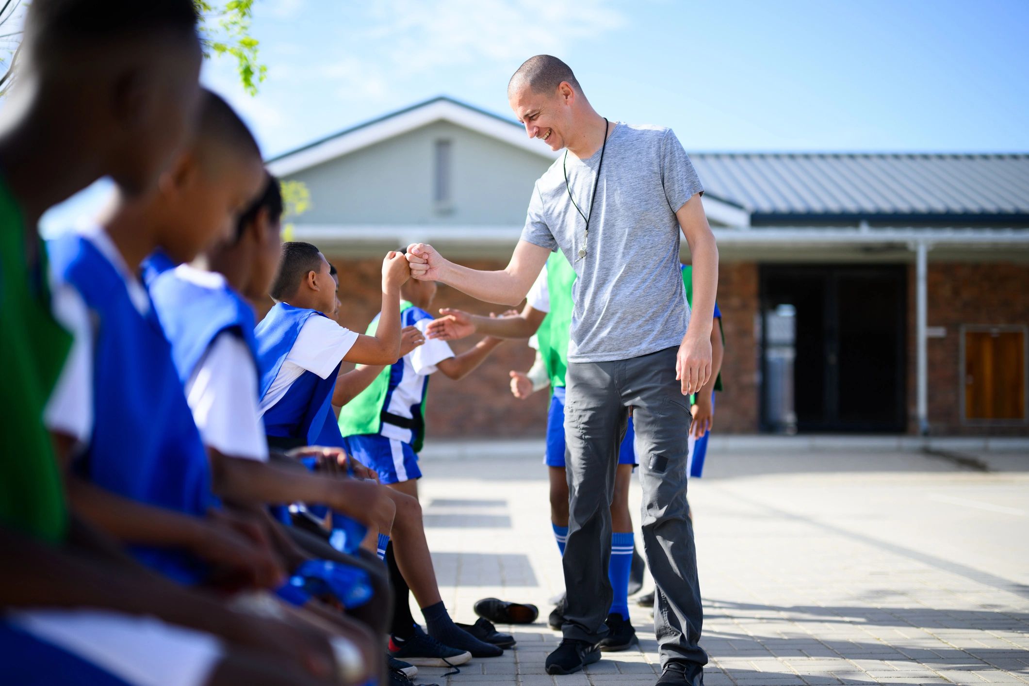 Coach greeting young soccer players before practice